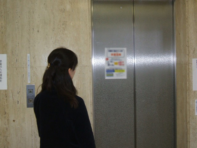 エレベーターにある広告を一人の女性が見ている様子の写真