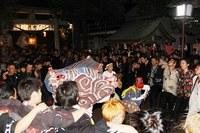 獅子舞を中心に、肩を組み輪になって踊る若衆