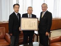 表彰状を手に、山辺市長らと記念撮影を行った蓮本嘉四郎さんの写真（中央）