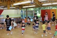 ホールで子どもたちと遊戯する羽咋白百合幼稚園の生徒たちの写真