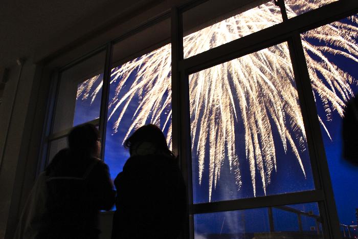 校舎の窓から花火を見る生徒ら