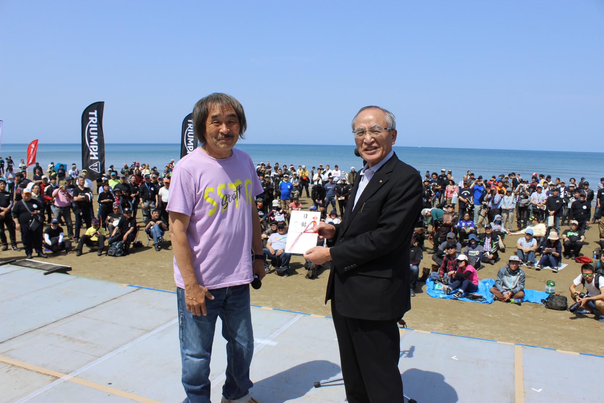 イベント発起人の風間深志さん（左）が山辺市長に寄付目録を贈呈