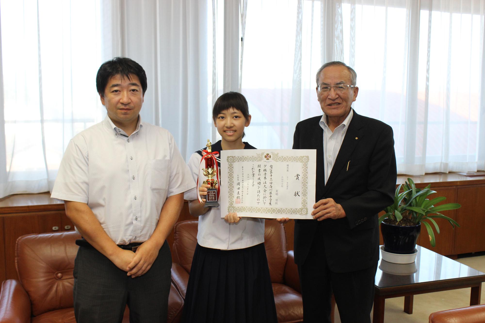 石川県中学生少林寺拳法大会で準優勝し、全国大会に出場する夏嶋里帆さん（中央）と指導者の畑山さん（左）